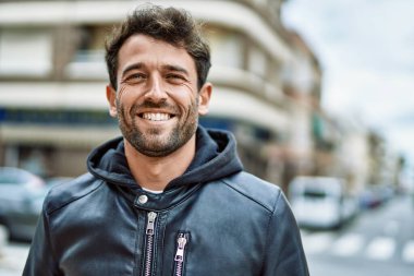 Yakışıklı, sakallı, açık havada mutlu gülümseyen bir İspanyol.