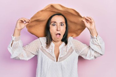 Orta yaşlı İspanyol kadın yaz şapkası takıyor. Şaşırmış ve şaşırmış bir ifade, korku ve heyecanlı bir yüz ifadesi var.. 