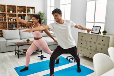 Genç Latin sporcu çift gülümseyerek evde mutlu bir antrenman yapıyor..