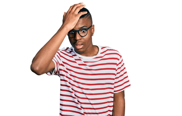 若いアフリカ系アメリカ人の男性は ミスのために頭の上に手で驚いて エラーを覚えてカジュアルなTシャツと眼鏡を着用 忘れられた悪い記憶の概念 — ストック写真