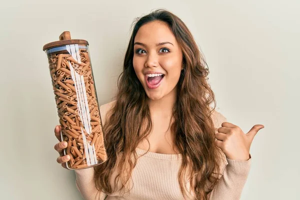 Menina Hispânica Jovem Segurando Jar Com Macarrão Macarrão Apontando Polegar — Fotografia de Stock