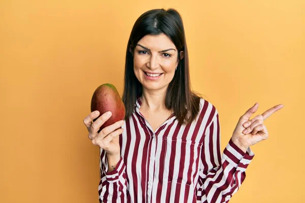 Junge Hispanische Frau Hält Mango Lächelnd Glücklich Und Zeigt Mit — Stockfoto