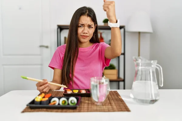 Mujer Morena Joven Comiendo Sushi Usando Palillos Enojado Loco Levantando — Foto de Stock