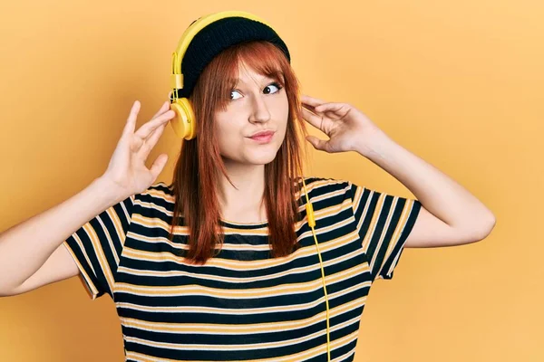 Kızıl Saçlı Müzik Dinleyen Kulaklık Takan Gülümseyen Yan Bakan Düşünen — Stok fotoğraf