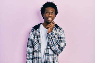 Genç, Afro-Amerikan bir adam günlük kıyafetler giyiyordu. Kuşku üzerine yoğunlaşmıştı. Parmakları çenesinde ve yukarı bakıyordu. 