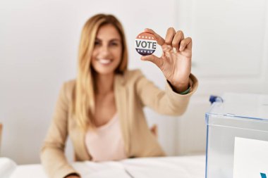 Genç Amerikalı siyasi parti çalışanı seçim kolejinde oy kartı tutuyor..