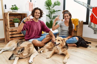 Genç İspanyol çift çamaşırlarını yıkıyor. Köpekler gülümsüyor ve elleriyle el hareketi yapıyor. Küçük boy işareti yapıyor. ölçüm kavramı. 