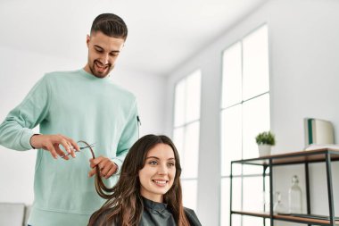 Genç İspanyol stilisti kadın saçını güzellik merkezinde makas kullanarak kesiyor..