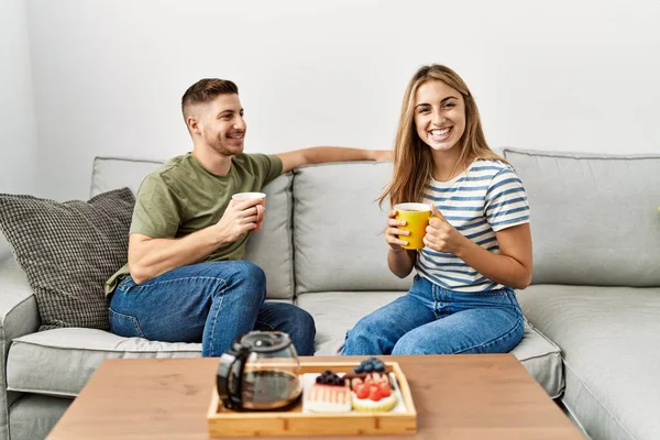 Jovem Casal Hispânico Sorrindo Feliz Tomando Café Manhã Sentado Sofá — Fotografia de Stock