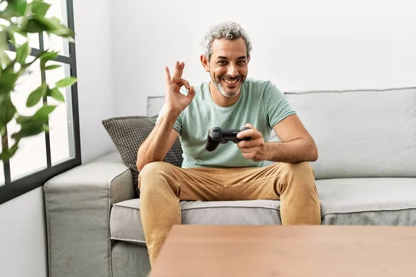 Homem Hispânico Meia Idade Jogando Videogame Sentado Sofá Fazendo Sinal — Fotografia de Stock