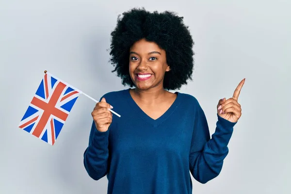 Молодая Африканская Американка Флагом Соединенного Королевства Улыбается Показывая Рукой Пальцем — стоковое фото
