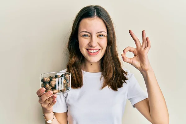 Ung Brunett Kvinna Håller Hasselnötter Gör Tecken Med Fingrar Ler — Stockfoto