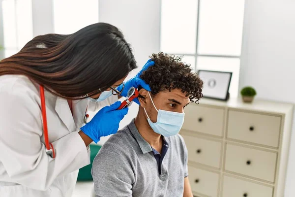 若いラテン語の医師の女性のための聴診器を使用して男の耳を会計検査室で — ストック写真