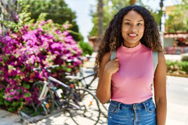 Genç İspanyol kız gülümseyerek şehirde mutlu mesut dikiliyor..