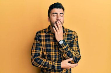 Gündelik kıyafetler giyen genç İspanyol adam ağzıyla ağzını kapatmaktan sıkılmış. Huzursuz ve uykulu.. 