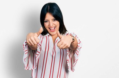 Latin asıllı genç bir kız günlük giysiler giyip olumlu jestler yapıyor. Elleriyle gülümsüyor ve başarı için seviniyor. kazanan jest. 