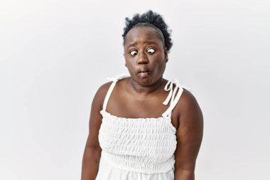 Genç Afrikalı bir kadın izole edilmiş beyaz arka planda duruyor dudaklarıyla balık suratı yapıyor, çılgınca ve komik bir jest. Komik ifade. 