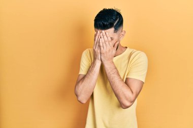 Sakallı, sıradan sarı tişörtlü, suratını ellerle örten ve ağlayan yakışıklı bir adam. depresyon kavramı. 