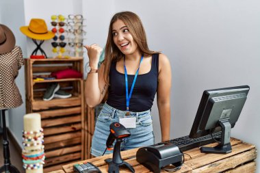 Genç esmer kadın perakende dükkanında açık mesajla pankart tutuyor. Gülümsüyor, gülümsüyor ve başparmağıyla yan tarafı işaret ediyor.. 