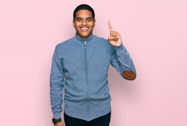 Gündelik kazak giyen genç, yakışıklı İspanyol adam başarılı bir fikri işaret ediyor. Heyecanlı ve mutlu. Bir numara.. 