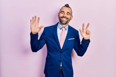 Genç İspanyol takım elbiseli ve kravatlı adam sekiz numaralı parmaklarını gösterip gösterirken kendinden emin ve mutlu gülümsüyor.. 