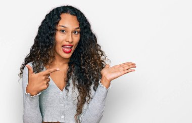 Kıvırcık saçlı genç İspanyol kadın kameraya hayret ediyor ve gülümsüyor.. 