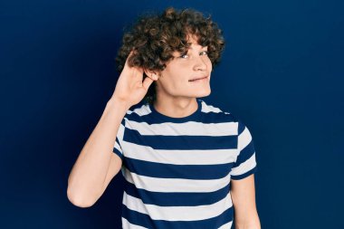 Sıradan çizgili tişört giyen yakışıklı genç adam. Kulağı kulağında gülümsüyor. Dedikoduları ve dedikoduları dinliyor. Sağırlık kavramı. 