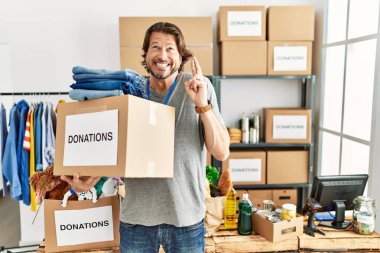 Gönüllü olarak bağış kutusunu tutan yakışıklı orta yaşlı bir adam umut ve gözleri kapalı gülümseyerek el sallıyor. Şans ve batıl inançlar. 