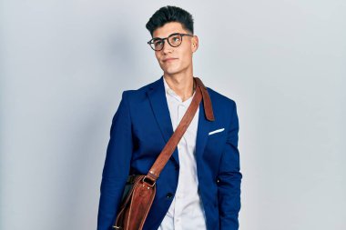 Genç İspanyol adam iş kıyafetleri içinde gülümseyip yan tarafa bakıyor ve düşünüyor.. 