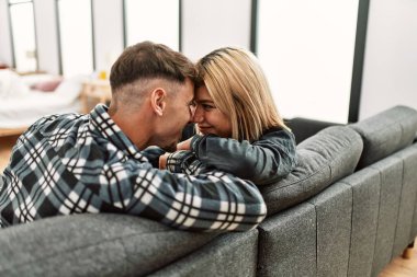 Evdeki kanepede otururken mutlu gülümseyen beyaz bir çift..