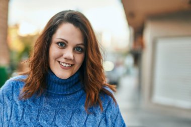 Genç İrlandalı artı cüsseli kız gülümseyerek şehirde mutlu mesut duruyor..