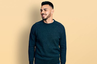 Sakallı, kışlık süveter giyen genç, rahat bir görünüm takınan, doğal yüzlü ve kendine güvenen bir gülümseme takınan bir İspanyol.. 