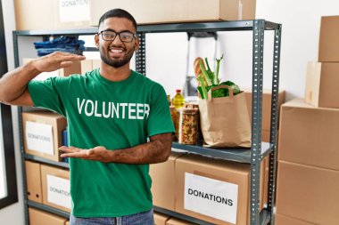 Genç Hintli gönüllü bağış kutusunu tutuyor. Ellerinde büyük ve büyük bir işaret var. Ölçüm sembolü. Kameraya bakıp gülümsüyor. ölçüm kavramı. 