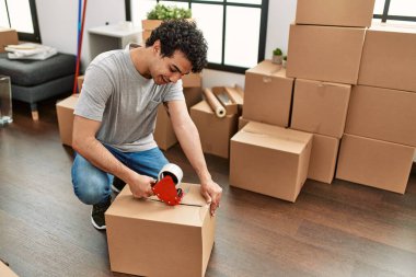 Genç İspanyol adam gülümsüyor yeni evinde mutlu bir paket kutusu var..