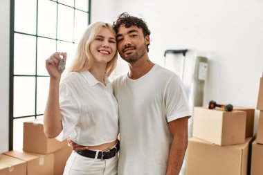 Genç ve güzel bir çift gülümsüyor. Mutlu mesut yeni evin anahtarını tutuyor..