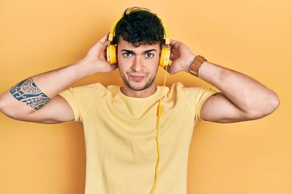 Young Hispanic Man Listening Music Using Headphones Skeptic Nervous Frowning — Stock Photo, Image