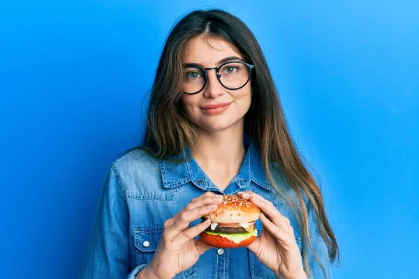 Mladá Běloška Která Chutný Klasický Burger Uvolnila Vážným Výrazem Tváři — Stock fotografie