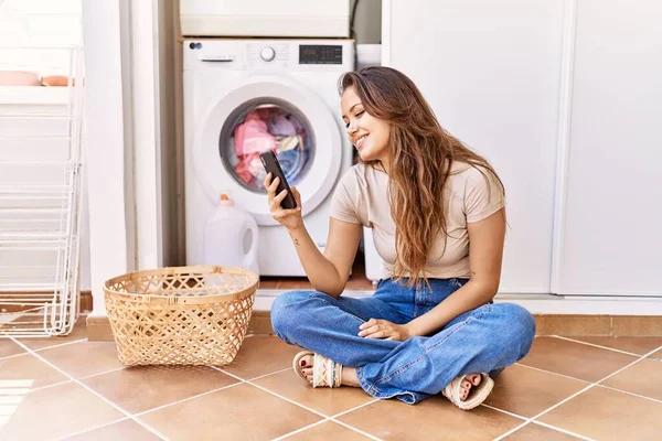 Ung Latinamerikansk Flicka Med Smartphone Väntar Tvättmaskin Hemma — Stockfoto