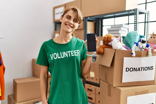 Jovem Mulher Voluntária Caucasiana Sorrindo Feliz Mostrando Aplicativo Voluntariado Centro — Fotografia de Stock