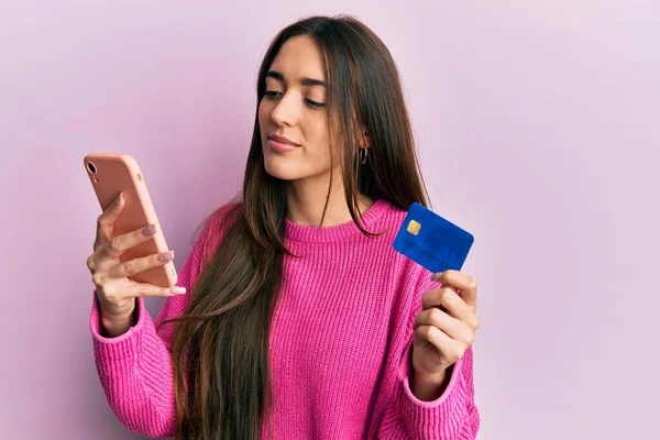 Młoda Latynoska Dziewczyna Trzymająca Smartfona Kartę Kredytową Zrelaksowana Poważnym Wyrazem — Zdjęcie stockowe