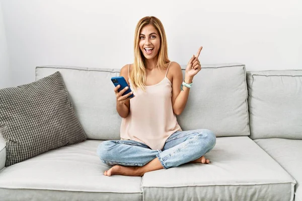 Blond Vacker Ung Kvinna Sitter Soffan Hemma Med Hjälp Smartphone — Stockfoto