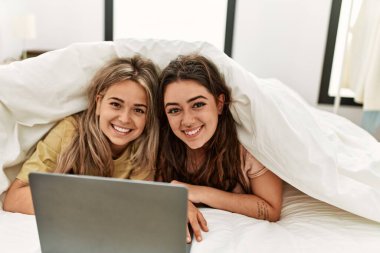 Yatakta çarşafla film izleyen genç çift..