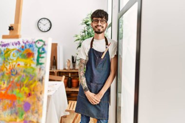 Genç İspanyol ressam mutlu bir şekilde resim stüdyosunda duruyor..