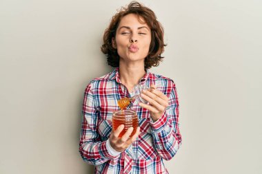 Genç esmer kadın taze bal tutuyor. Kameraya bakıyor. Öpücük atıyor. aşk ifadesi. 