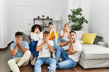 Bir grup insan evdeki koltukta ve yerde otururken yanlışlıkla ağızlarını kapatarak şok geçirdiler. gizli kavram. 