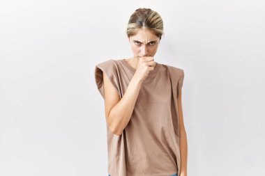 İzole edilmiş arka planda duran genç sarışın kadın kendini iyi hissetmiyor ve soğuk algınlığı veya bronşitin belirtisi olarak öksürüyor. sağlık hizmeti kavramı. 