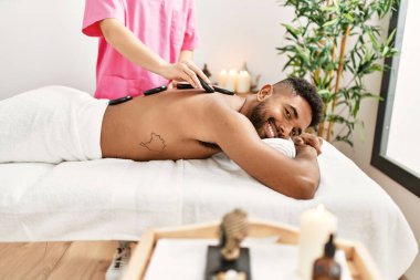 Güzellik merkezinde siyah taşlarla masaj yaptıran adam..