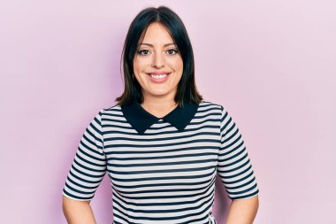 Yüzünde mutlu ve havalı bir gülümseme olan gündelik kıyafetler giyen genç İspanyol kadın. şanslı kişi. 