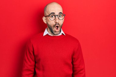 Genç kel bir adam günlük kıyafetler ve gözlük takıyor. Şaşırmış ve korkmuş bir ifade, korku ve heyecanlı bir yüz ifadesi var.. 