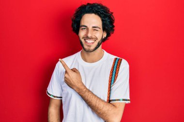 Yakışıklı ispanyol adam parmaklarını yana doğru gösteriyor kameraya seksi bir ifadeyle bakıyor, neşeli ve mutlu bir yüzle.. 